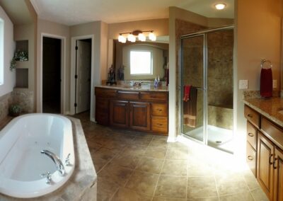 Jacuzzi bathroom with oval tub and clear glass tile shower.