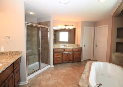 Large bathroom with clear glass tile shower and whirlpool tub.