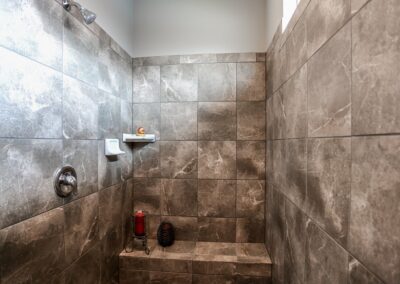 Walk in shower w/ bench seat & earth tone tile by Aurora Homes Omaha, NE
