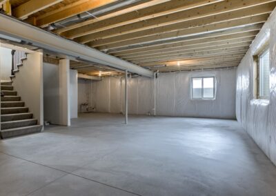 Large unfinished basement with large windows and concrete floor.