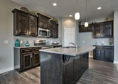 Omaha Home Builders kitchen with island sink dark cabinets.