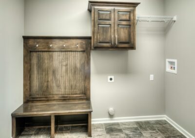 Mud room with stained birch bench seat and laundry cabinet.