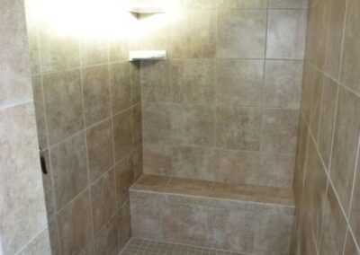 Walk in shower with tile seat and bright window.