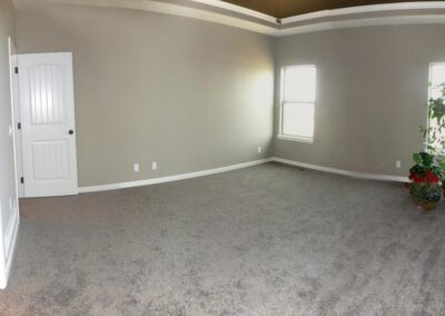 Primary bedroom with raised ceiling, accented paint, and crown molding in Omaha, NE.