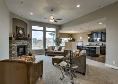 Furnished family room and kitchen with stone covered gas fireplace presented by Aurora Homes in Omaha, NE.