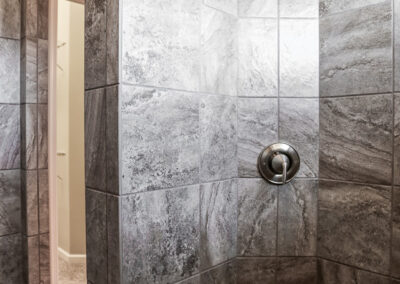 Walk in shower with grey swirl tile.