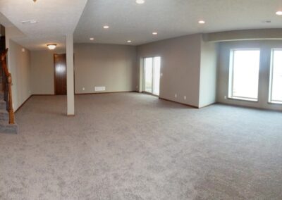 Finished Basement family area with large windows and grey carpet.