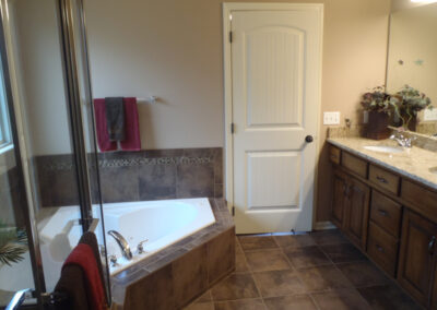 Triangular whirlpool tub with earth tone tile accents and stained birch vanity.