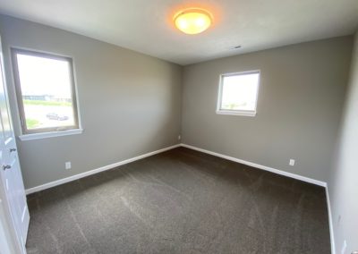 Bedroom with two windows, light grey carpet, and white woodwork.