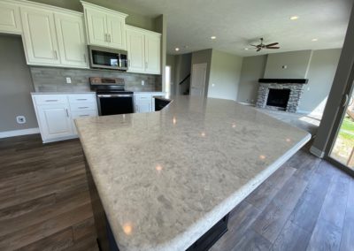 Quartz kitchen island top with cabinets and gas fireplace in background