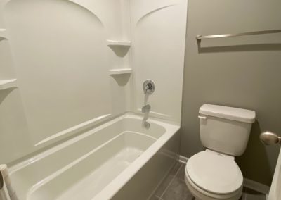 Shower, bathtub, and stool with grey tone finishes.