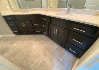 Bathroom vanity with two sinks, black cabinetry, and quartz countertops.