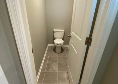 Separate toilet room with grey tile and white woodwork.