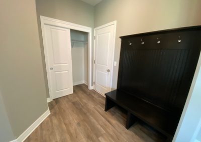 Garage rear foyer with bypass closet and black birch bench coat rack.