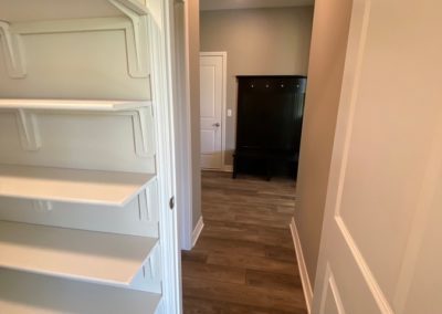 Walk through pantry with wood shelves by Aurora Homes Papillion, NE.