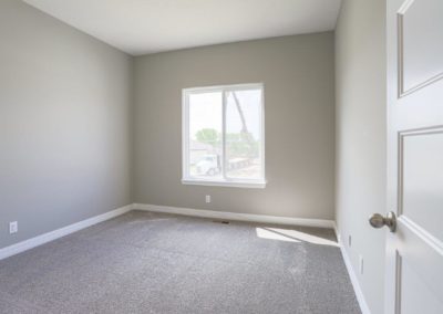 Bedroom with big window, white woodwork and grey toned carpet.