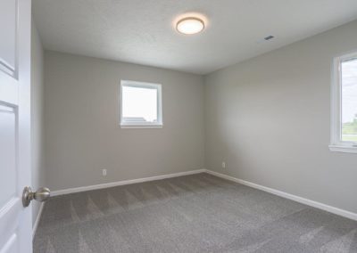 Unfurnished bedroom with two windows white woodwork, and grey carpet.