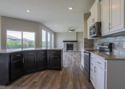 Kitchen with large island. Gas fireplace and large windows in the background.