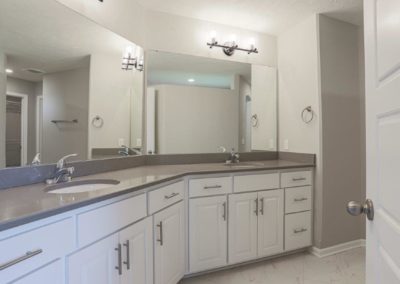 Bathroom vanity with 2 sinks, painted white woodwork, and grey quartz counter top.