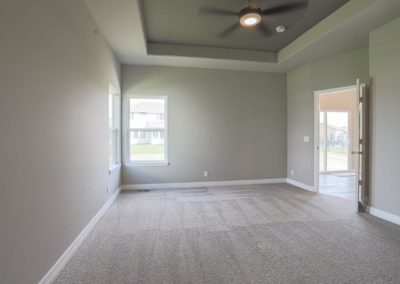 Master Bedroom with corner windows, grey carpet and accented raised ceiling.