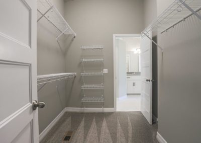 Clean walk in closet with tall ceiling by Aurora Homes.