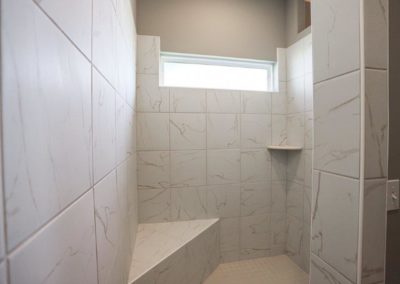 Walk in shower with privacy window, bench seat, and shelf by Aurora Homes Omaha, NE