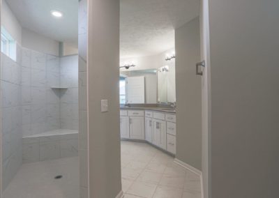 Bathroom with walk in shower, bench seat, 2 sinks and grey tone / white colors.