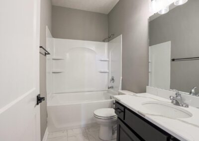 Bathroom with white quartz countertop and birch cabinets stained black.