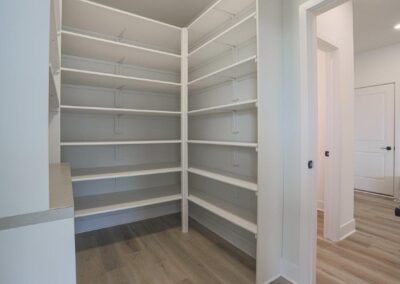walk through pantry with white wood shelves
