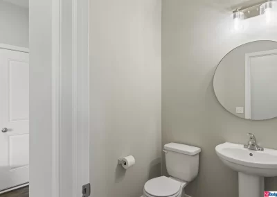 powder bathroom with round mirror and pedestal sink