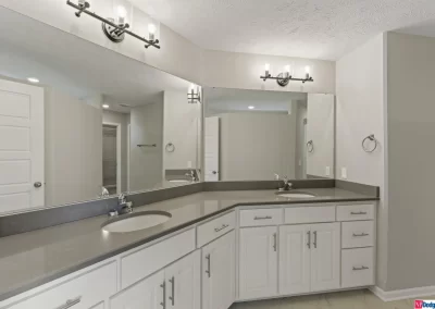 large bathroom with 2 sinks and white cabinets by Aurora Homes