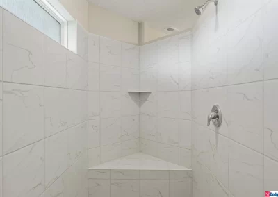 large tile shower with seat and window by Aurora Homes in Omaha